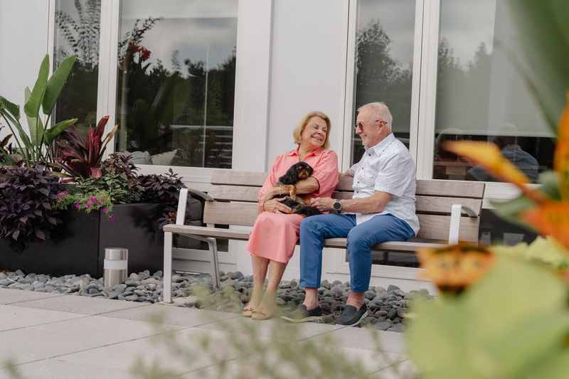 Residents relaxing with their dog on a bench in the outdoor courtyard