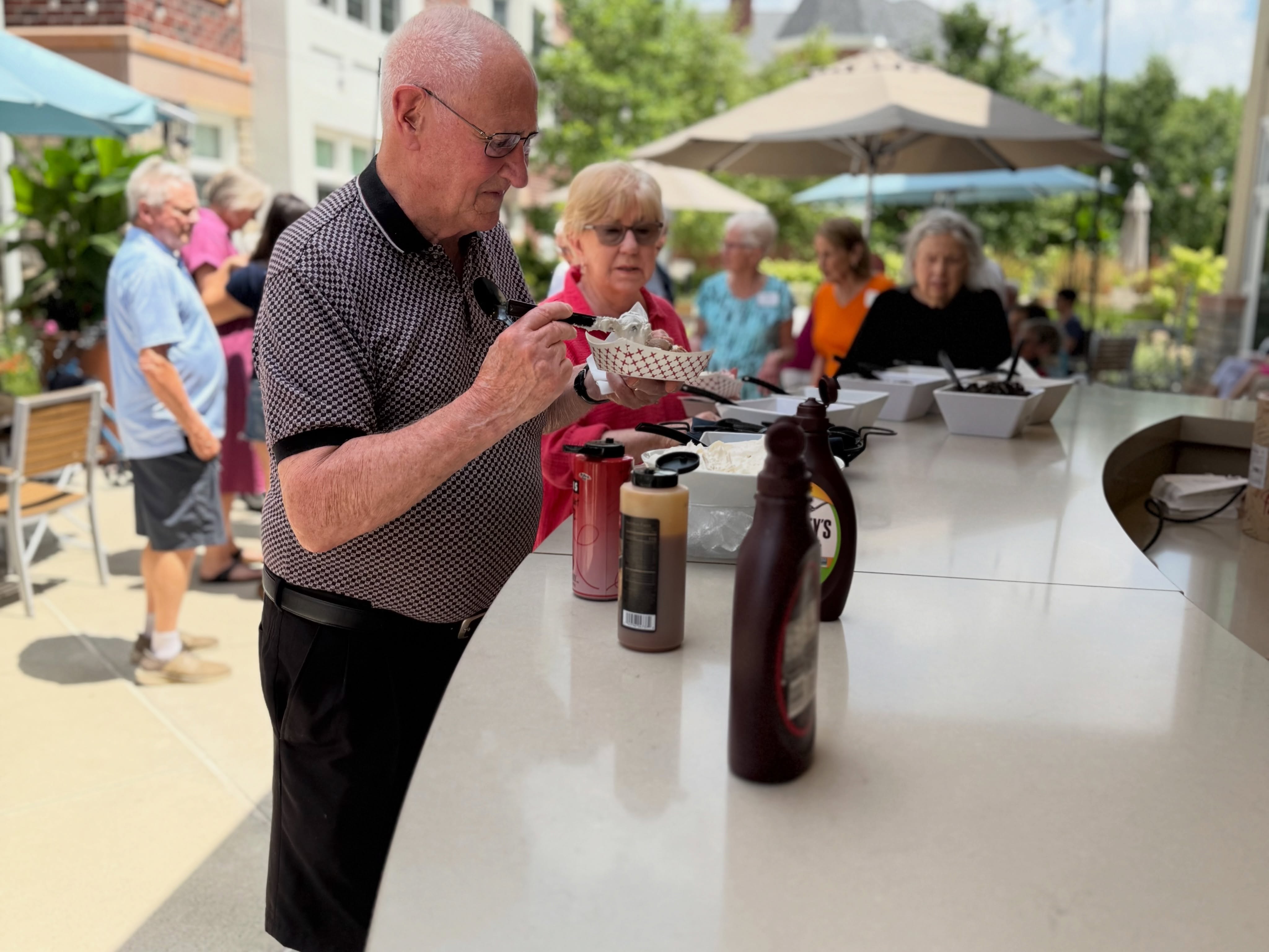 Resident pouring wine at an outdoor gathering